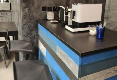 Communal break area featuring a blue-and-wood paneled coffee bar with a modern espresso machine.