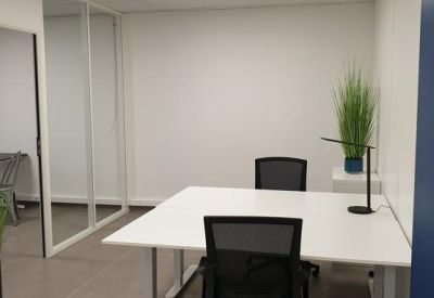 Private office suite with a white desk, black mesh chairs, and indoor plants.