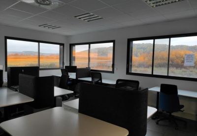 Bright open-plan workspace with multiple desks and large windows overlooking a scenic landscape.