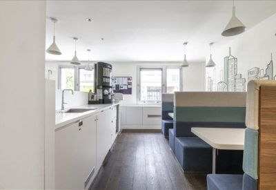 Bright communal kitchen and breakout area with booth seating and city skyline wall art.