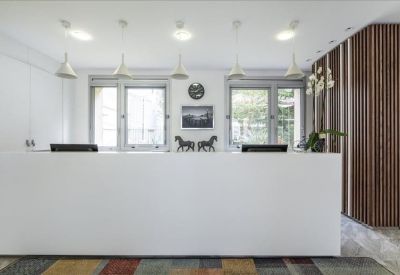 Bright white reception area with a minimalist front desk and wood-slat feature wall.