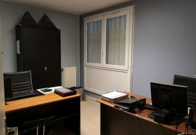 Two-person private office with wooden desks, computers, and a black storage cabinet.