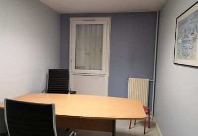 Small consultation room or office featuring a wooden table and framed wall art.