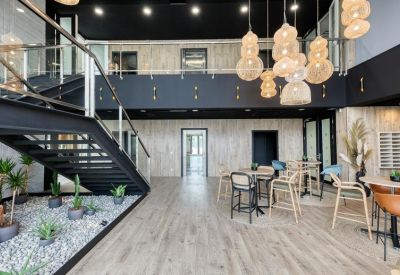 Double-height lobby featuring a black staircase, pebble garden, and stylish woven pendant lights.