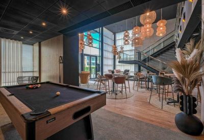 Breakout area with a pool table, cafe seating, and tiered decorative lighting.