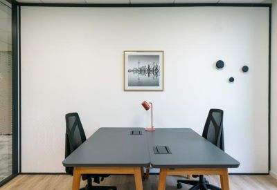 Two-person workstation setup with a framed cityscape photo and minimalist wall hooks.