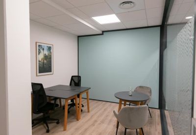 Private office featuring a desk and separate round meeting table with a light blue accent wall.