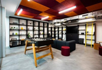 Breakout room with a foosball table, dark shelving, and colorful ceiling panels.