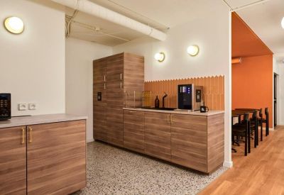 Modern communal kitchen area with wood-grain cabinetry and a sleek coffee station.