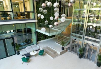 Bright multi-story atrium with a green wall and glass elevators.