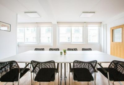 Bright conference room with a large white table and black mesh chairs.