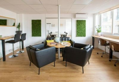 Bright coworking area with a variety of seating including leather armchairs and high stools.