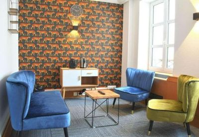 Cozy meeting corner with a tiger-print feature wall and blue and yellow velvet armchairs.