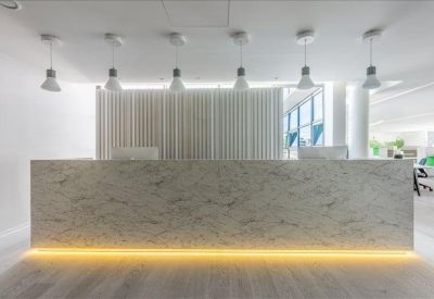 Sleek marble reception desk illuminated by warm under-counter lighting and hanging lamps.