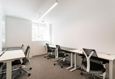 Private office space with several white workstations and ergonomic mesh chairs.