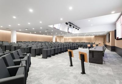 Large tiered lecture hall at 26 Rue de Montholon with grey seating and wood-panelled walls.