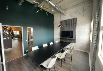 Modern meeting room with a long black table, white chairs, and a dark accent wall.