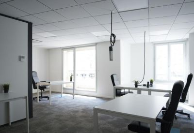 Bright, white open-plan office with multiple desks and ergonomic black chairs.