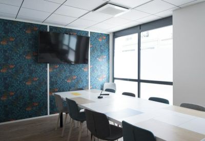 Modern meeting room featuring a bold blue floral patterned feature wall and a long white table.