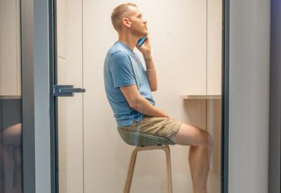 Single occupancy phone booth with a high stool for private calls.