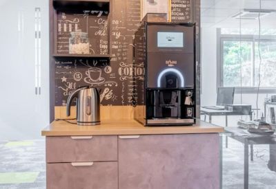 Self-service coffee station with chalkboard-style wallpaper and a professional machine.
