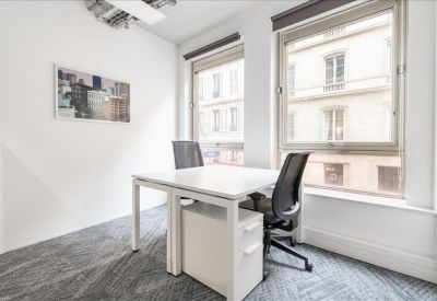 Private office featuring a white desk, ergonomic chair, and large windows with street views.