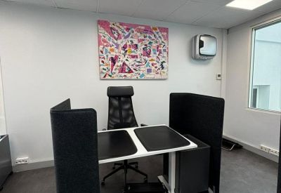 Individual workspace with a black privacy screen, ergonomic chair, and vibrant abstract artwork.
