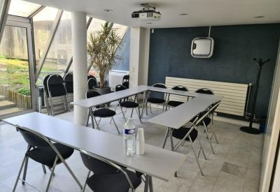 Sun-drenched meeting room with a U-shaped table setup and glass walls looking out to a patio.