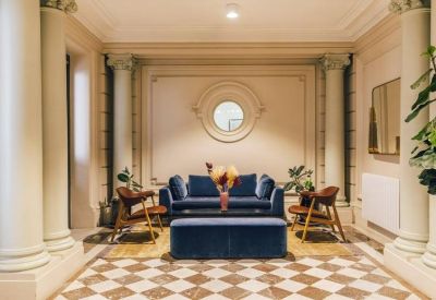 Reception area with classical columns and a blue velvet sofa.