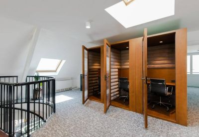 Private wooden phone booths for focused work under a skylight.