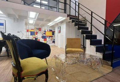 Reception area showing a modern staircase, colorful feature wall, and a yellow velvet chair.