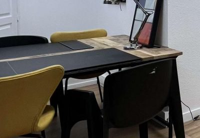 Wooden meeting table with black and yellow chairs and abstract wall art.