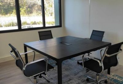 Small meeting room with a square dark wood table and four ergonomic chairs.