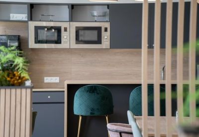 Close-up of a contemporary kitchenette with built-in microwaves and velvet bar stools.