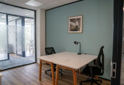 Minimalist two-person office suite with a clean white desk and teal accent wall.