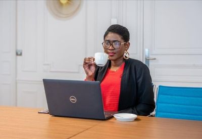 Professional working on a laptop at a wooden desk with a white cup.
