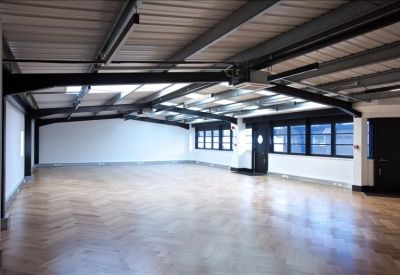 Spacious open-plan office featuring chevron wood flooring and industrial steel beams.