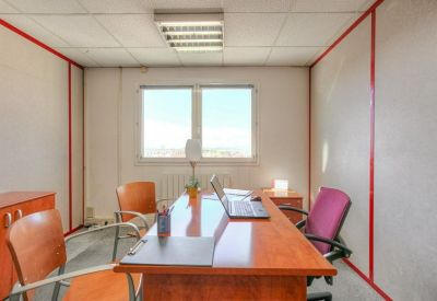 Sunlit meeting room with a wooden table, ergonomic chairs, and large windows.