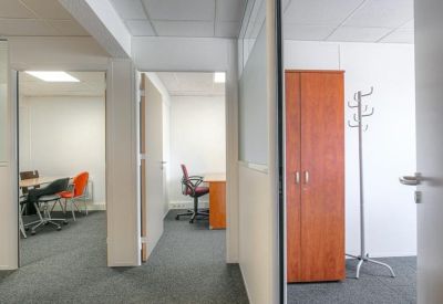 Bright office corridor showing a glimpse into a private workspace and a lounge area.