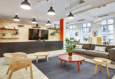 Bright communal lounge with a large TV, wooden furniture, and vibrant indoor plants.