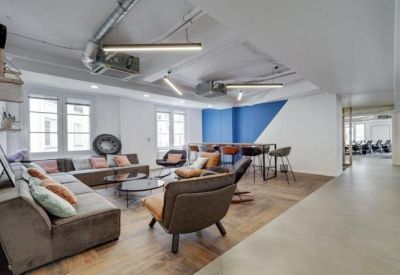 Modern breakout area featuring a large grey sectional sofa and stylish blue accent wall.
