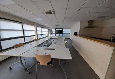 Large U-shaped meeting table set up in a room with a kitchen breakfast bar.