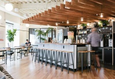 Bright café area with a tiled service bar, wooden ceiling beams, and stool seating.