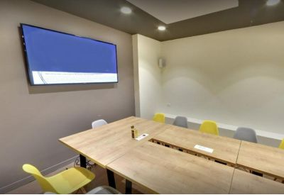 Bright meeting room with a large wooden table and colorful chairs.