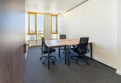 Small meeting room with four black chairs and bright windows.
