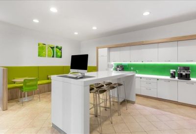 Modern breakout kitchen and dining area with lime green accents and white cabinetry.