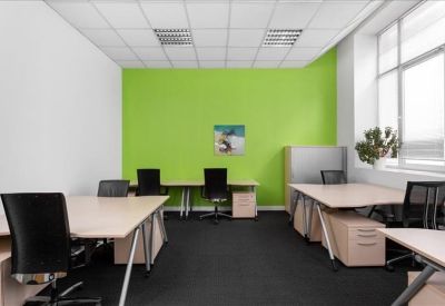 Spacious open-plan office with a vibrant lime green feature wall and modern white desks.