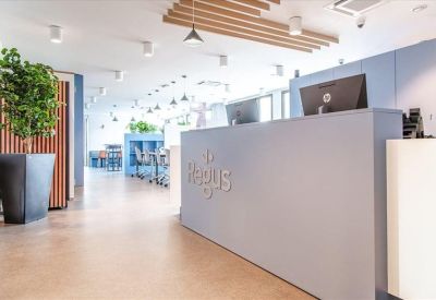 Modern reception area featuring a large grey desk with the Regus logo and wooden ceiling accents.