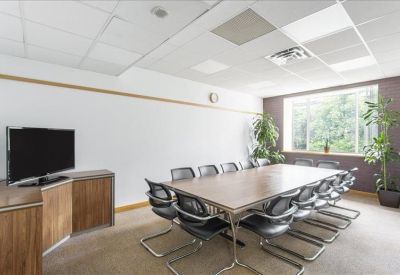 Professional boardroom with a large table, monitor, and natural light.