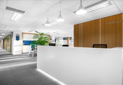 Bright reception area featuring a minimalist white desk and a warm wood-slatted feature wall.